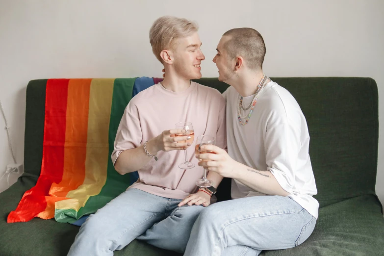 two guys sitting on a couch with glasses