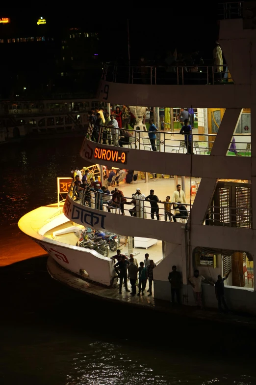 people standing on the deck of a large ship at night