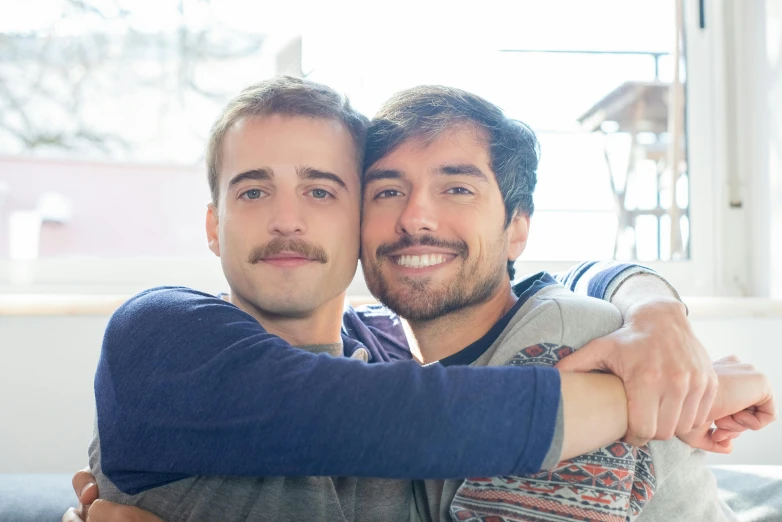 two smiling men emcing each other with one arm around the other