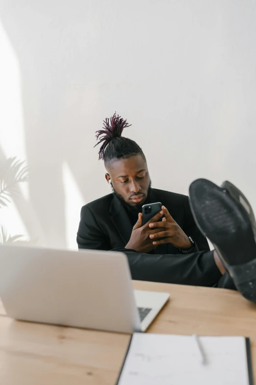 a man sitting in front of a computer and holding a cellphone