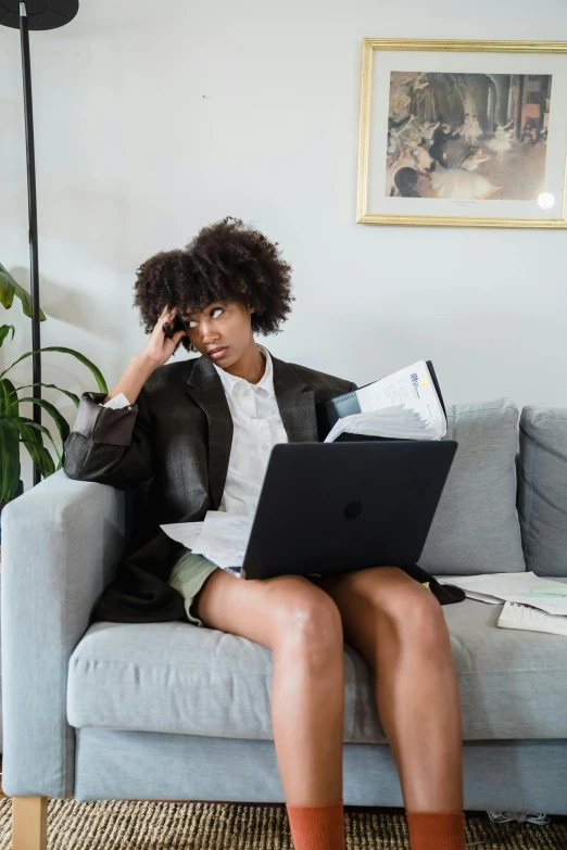 a woman sitting on a couch, with her laptop computer