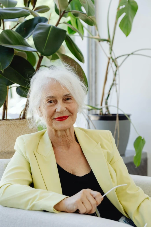 an old lady sitting on a chair in front of a potted plant