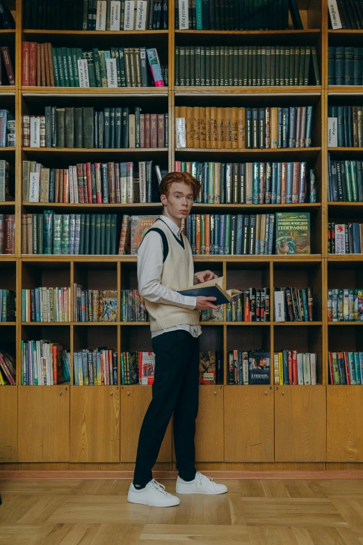 a person is standing by a book case and reading