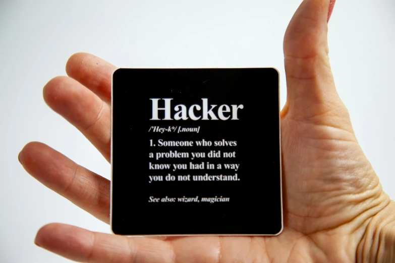a person holding a coaster with the words hacker written on it