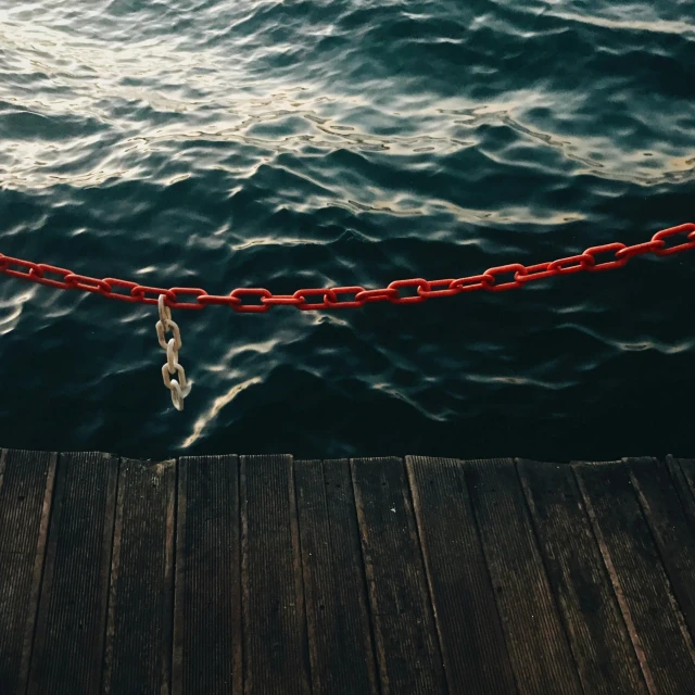 a red rope attached to a dock next to the ocean
