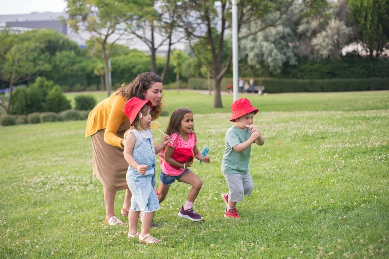 three children with adult on grassy field next to trees