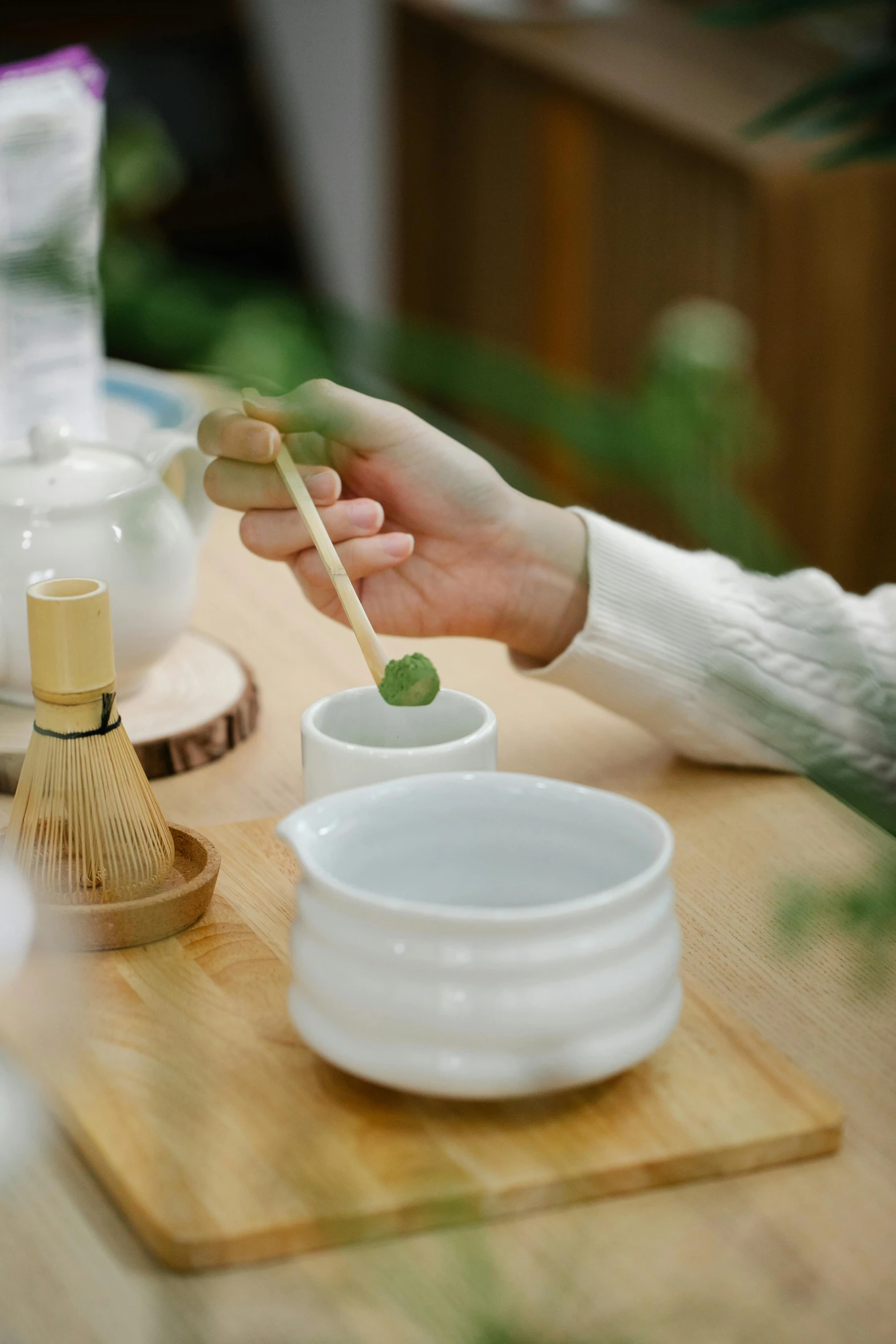 person holding a bamboo stick over bowls on a table