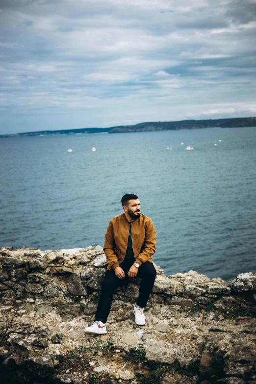 a man sitting on a rock next to the ocean