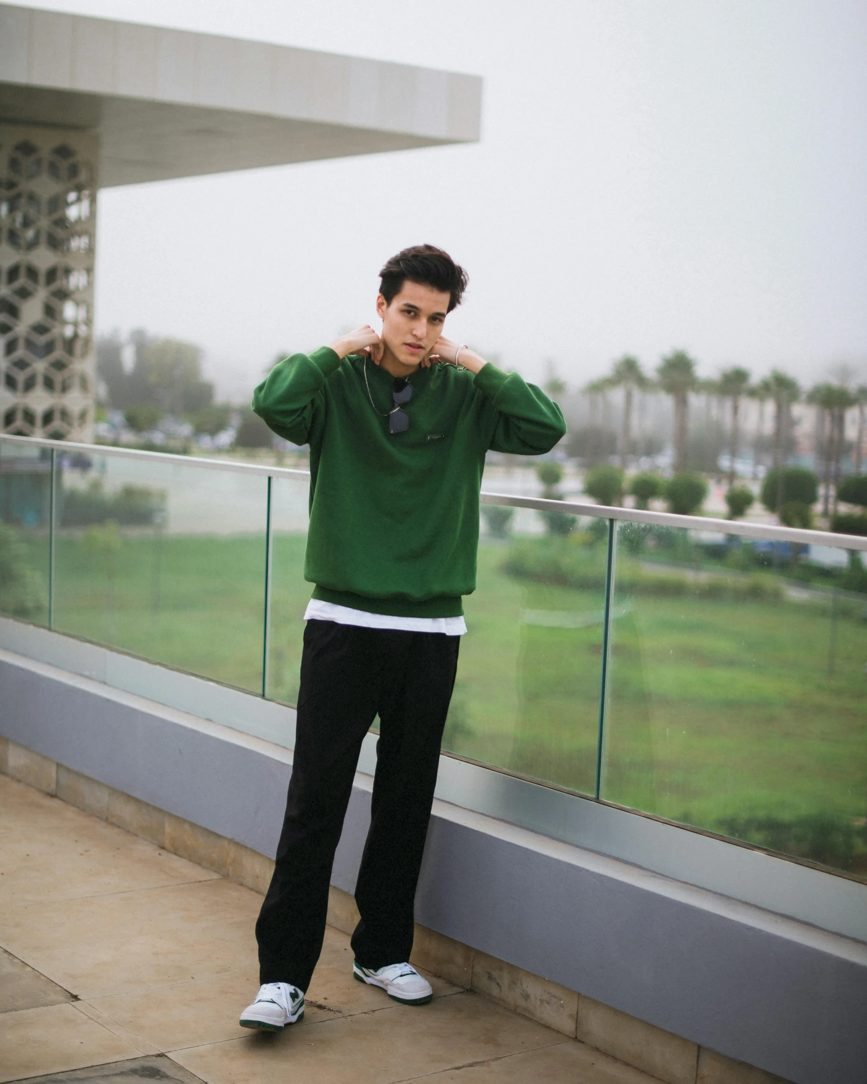 a young man standing outside holding his head and covering his ears