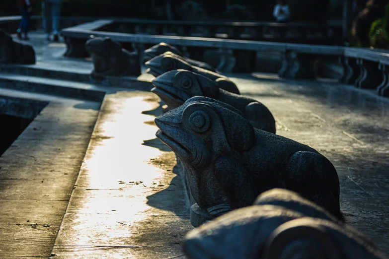 four stone sculptures of animals sit on concrete benches at a park