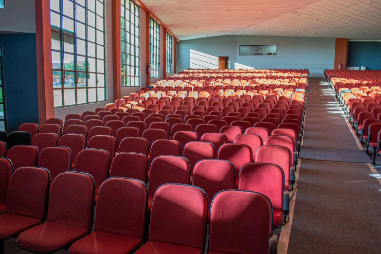 a set of empty rows of chairs sit in front of a projection screen