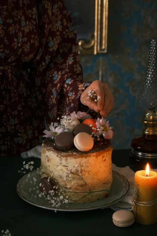 a woman in a long dress decorating a cake with flowers