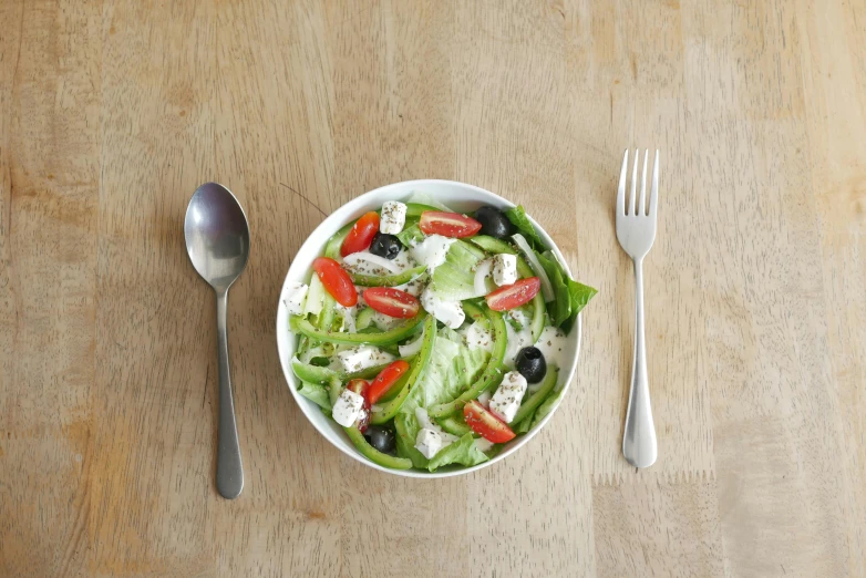 a salad in a bowl with dressing and some silverware