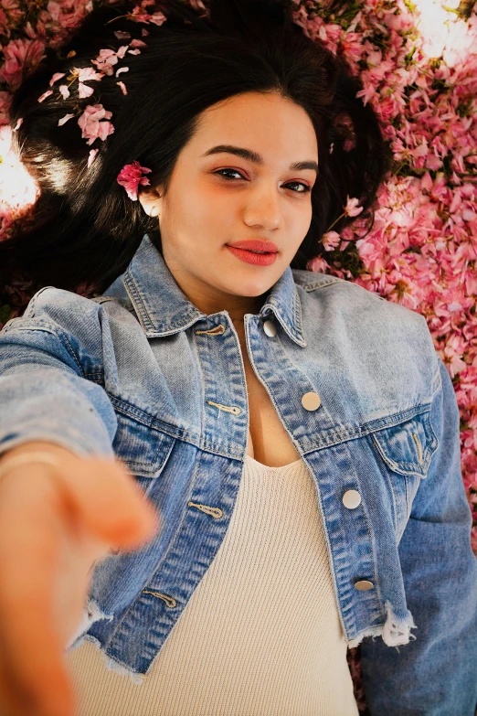 a woman pointing with her finger towards a rose wall