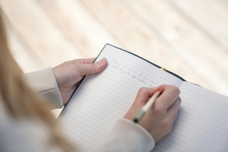 a woman is writing on a note book