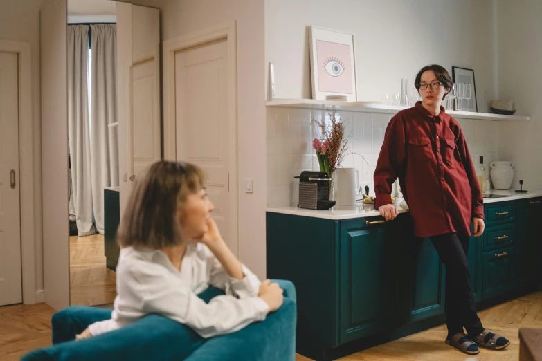 two people sitting on couches in front of a kitchen