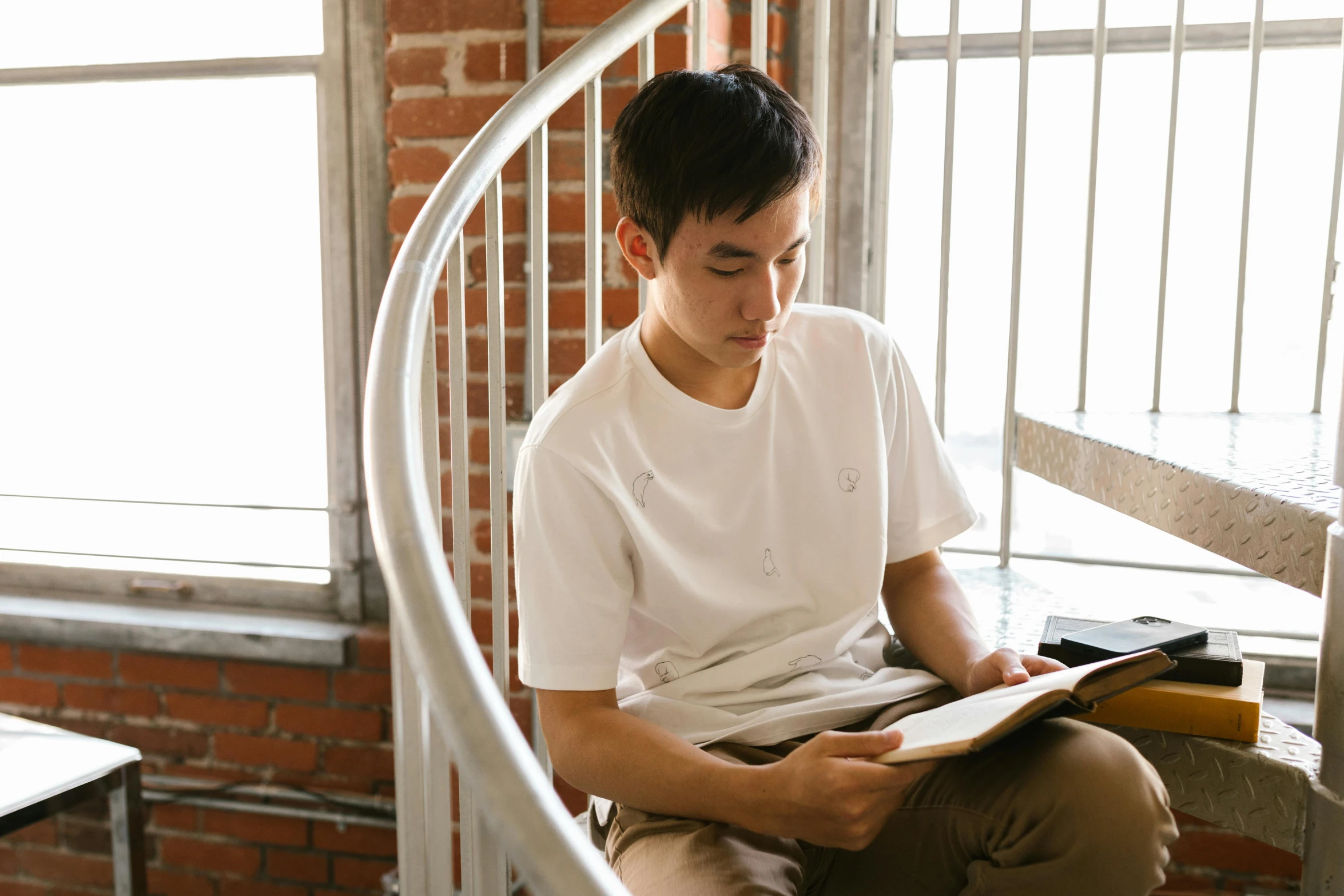 a young man sits on a spiral staircase and looks down