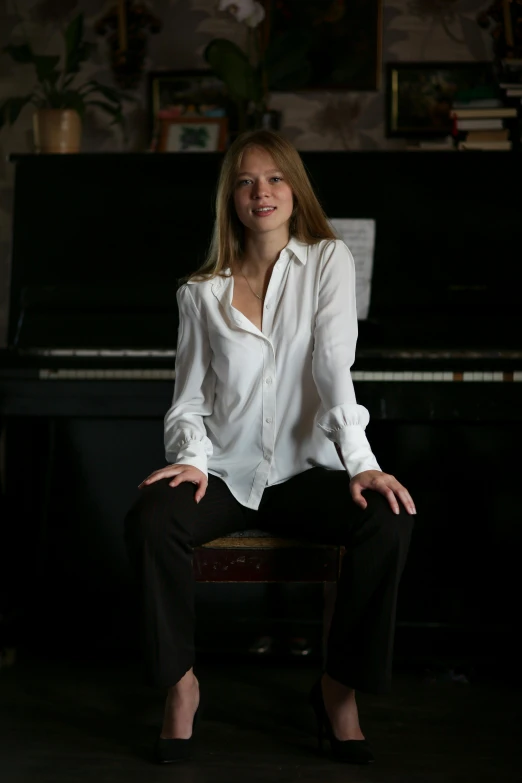 a woman sits near a piano with one foot up