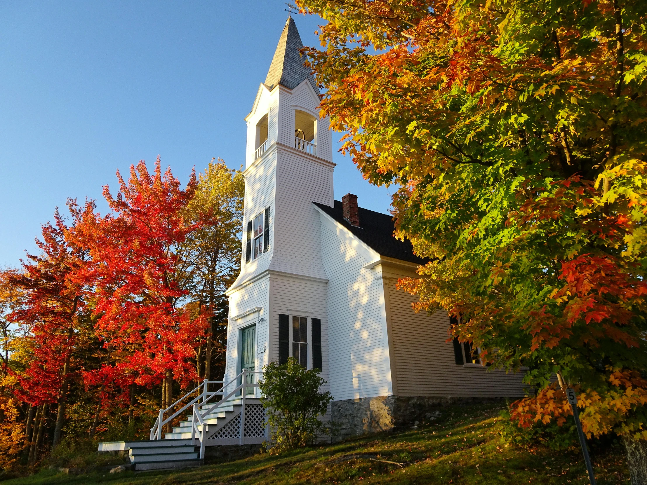 a white church surrounded by fall foliage