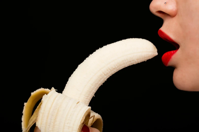 a close up of a woman eating a ripe banana