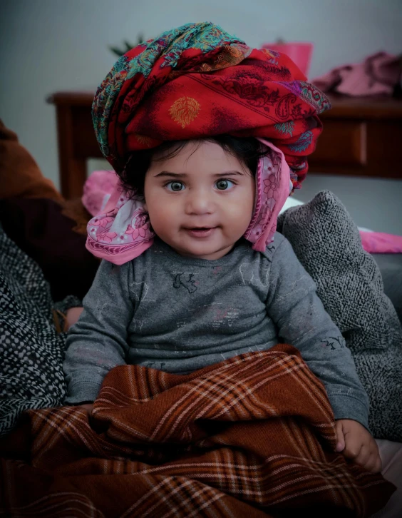 the child is wearing a red hat while sitting down