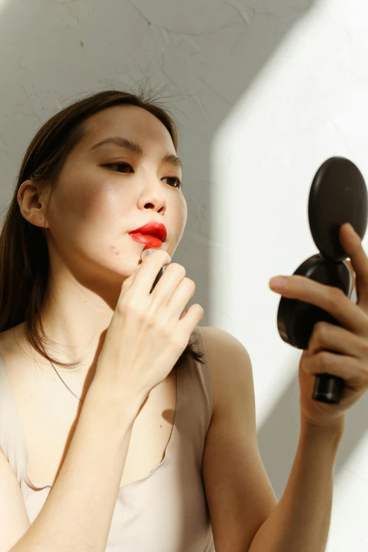 a woman with bright red lipstick, holding a round object