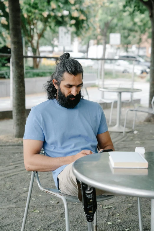 a man with a beard sitting at a table with a cup of coffee in his hands