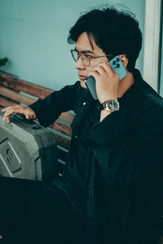 man in black jacket talking on cellphone with suitcase