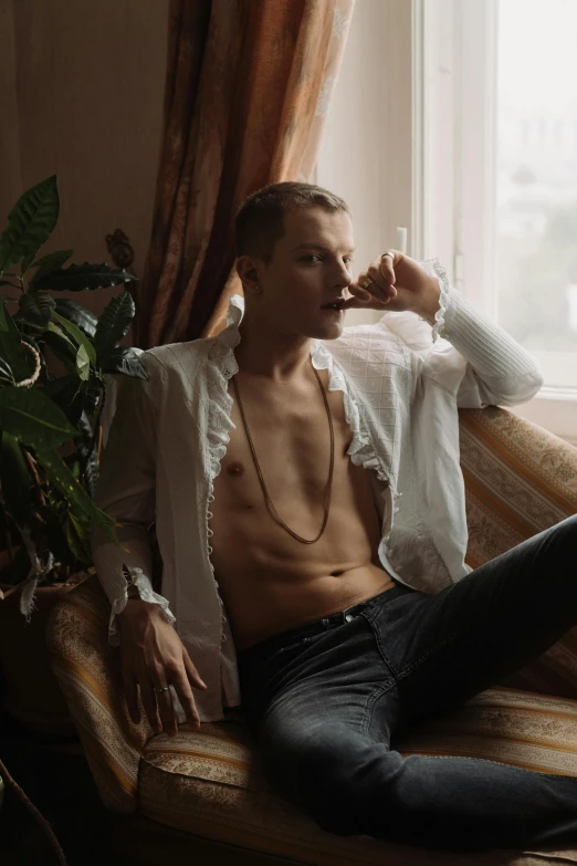 man in white shirt sitting on sofa drinking from a cup