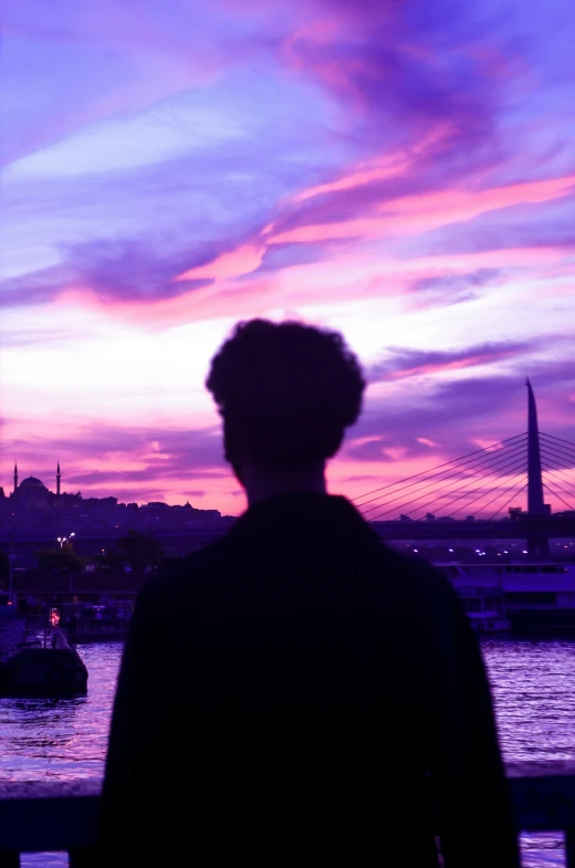 the back end of a person standing in front of a purple and blue sky