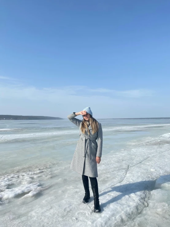 a woman in a plaid jacket on a lake shore