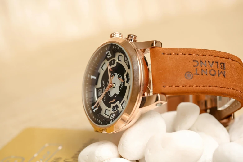 a gold watch with brown leather strap and white rocks