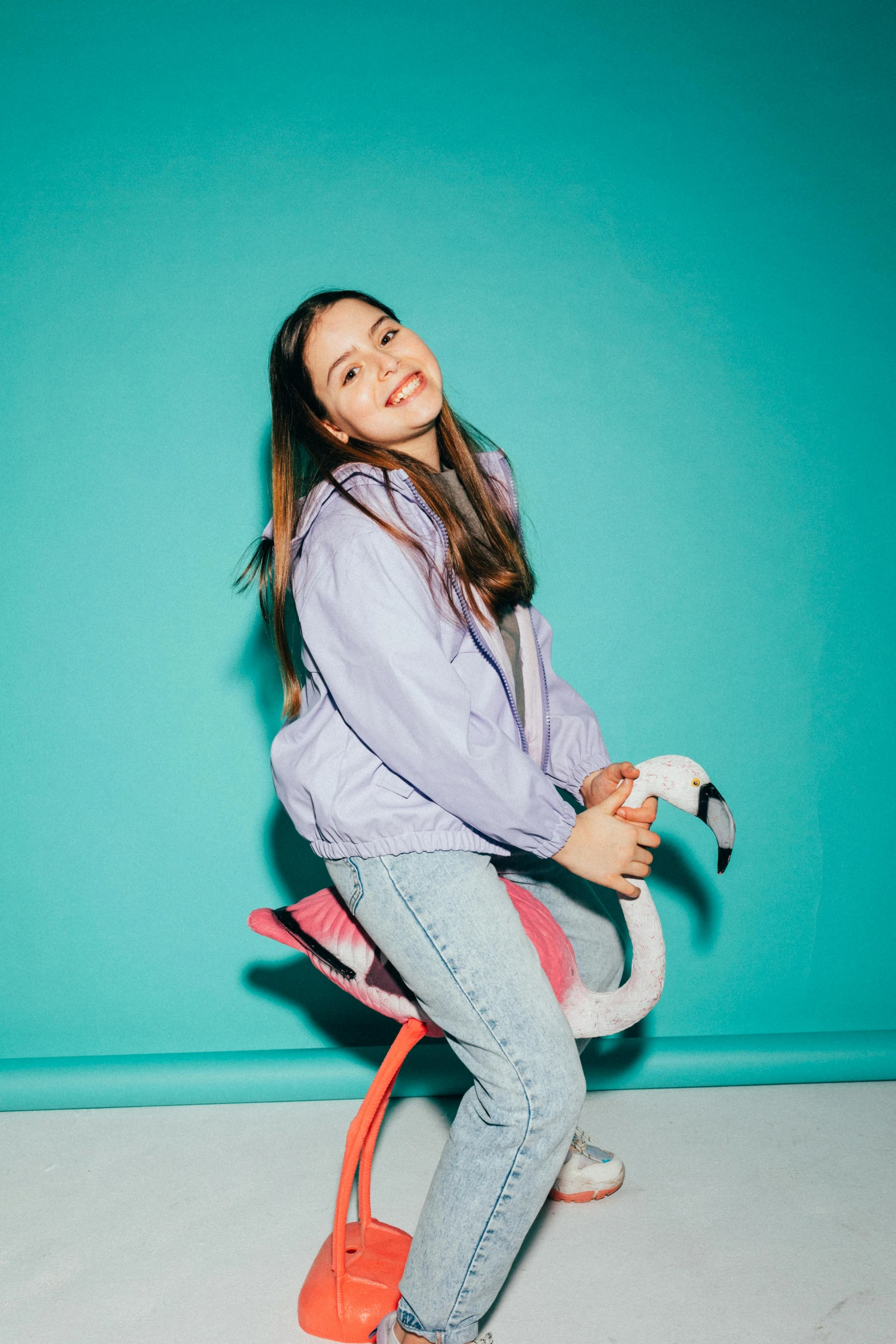 a girl sitting on a flamingo toy