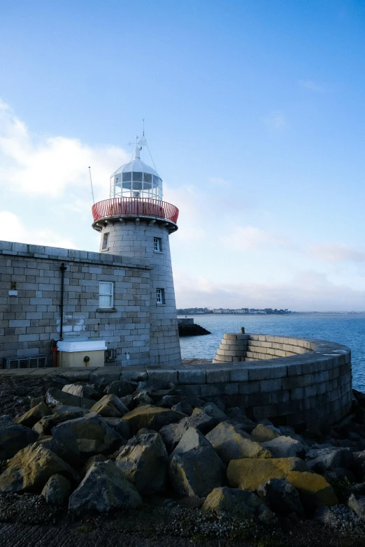 a lighthouse on a large rock shore next to a body of water