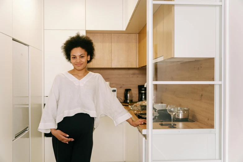 a lady in her kitchen poses with one hand on her waist