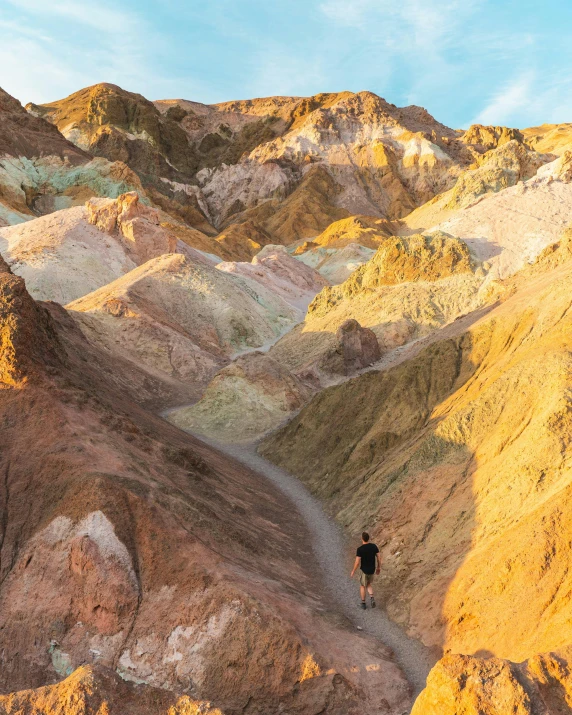 a man standing on top of a mountain next to colorful hills