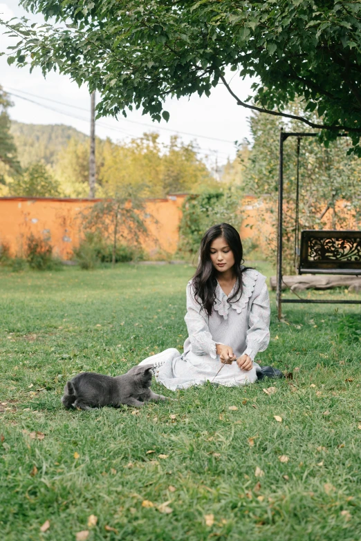 a woman sitting in the grass with her dog