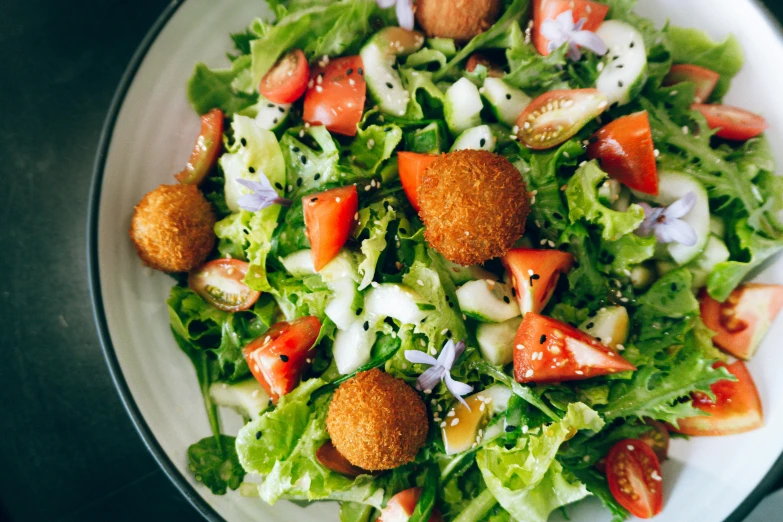 a salad sits on a white plate with lettuce, tomatoes, onions and other ingredients