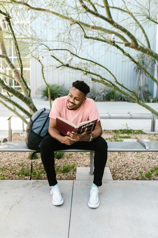 a man with a backpack sits reading a book