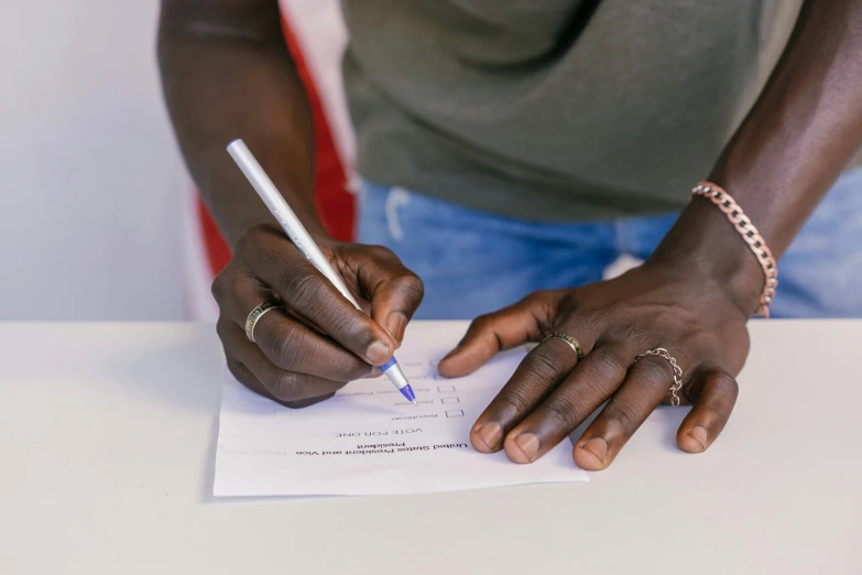 a person sitting at a desk writing with a pen and paper