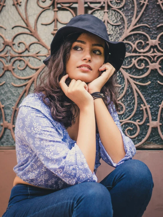 a young woman sits on a bench with her hat up