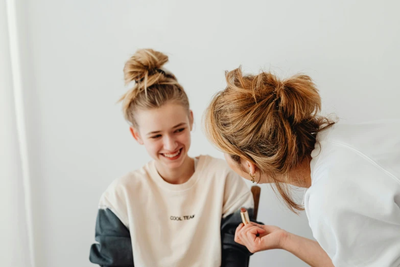 two girls are smiling and getting help with their makeup
