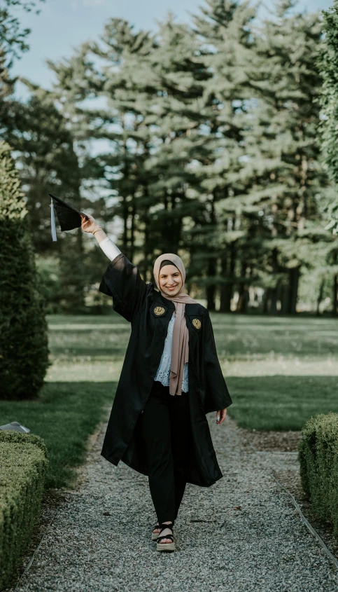 a woman walking down a walkway with her graduation gown