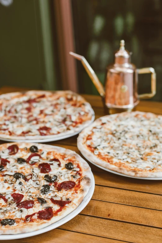 three pizzas sitting on top of a wooden table