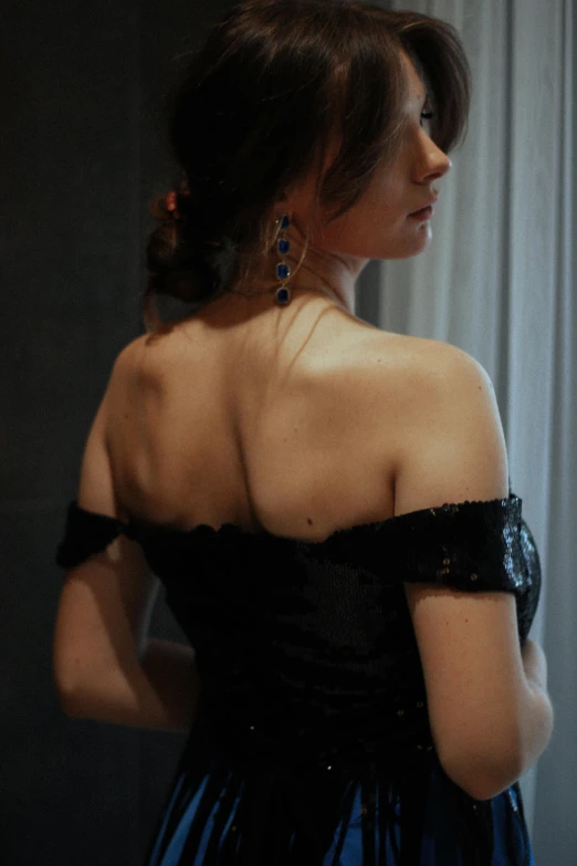 a woman in a black and blue dress looking out a window