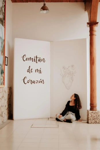 woman sitting on the floor looking at a wall with writing