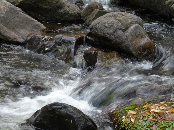 several large rocks in the water, one above a waterfall