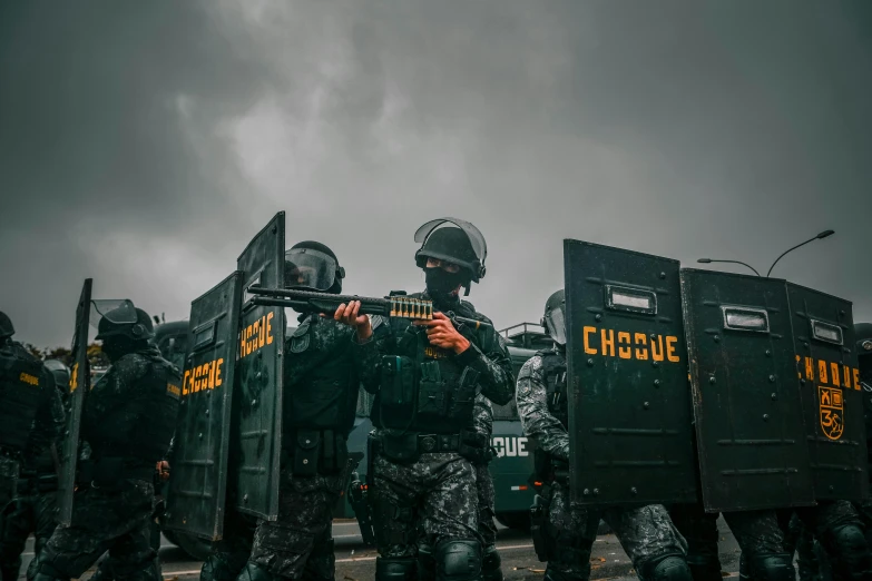 there are several policemen in riot gear and one is holding his rifle