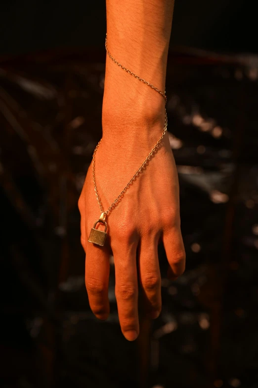 a hand holding onto a celet with a gold charm on it