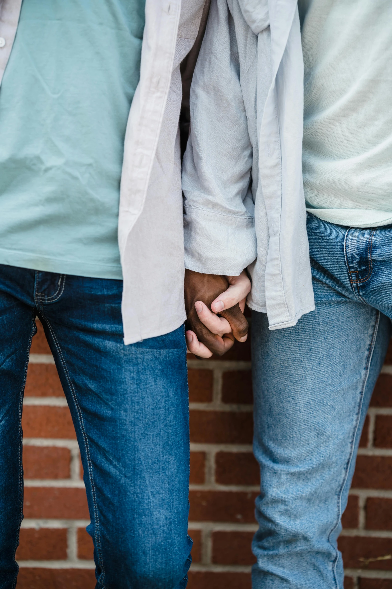 some people hold hands near a brick wall